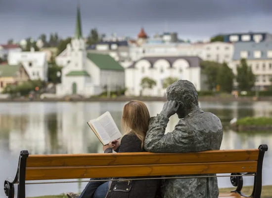 Womman sitting next to sitting statue at Tjarnargata 30 Reykjavik