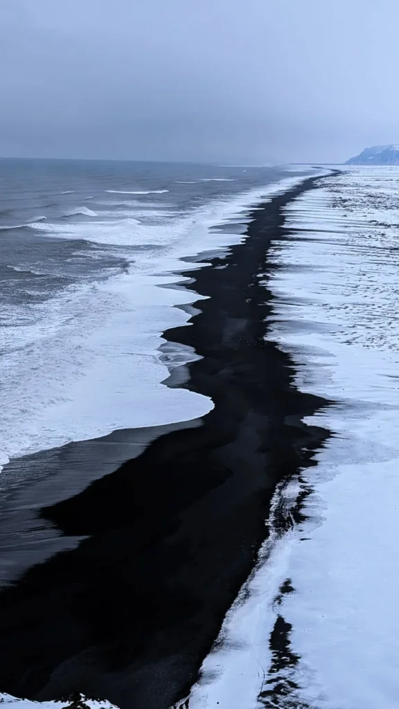 A black sand beach with snow on Iceland's south coast