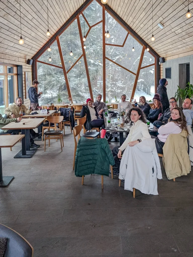 The group around the table in a wooden lodge with snow outside